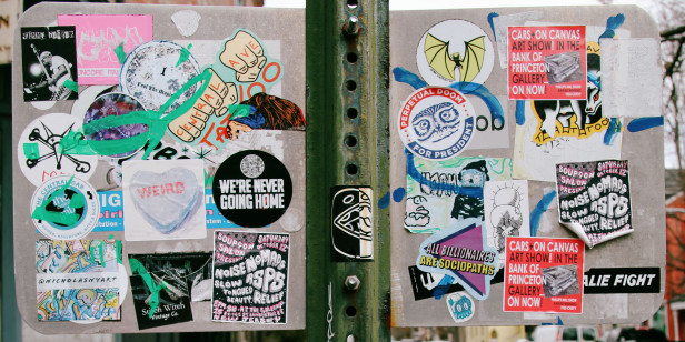 An array of stickers on the back of a street sign.