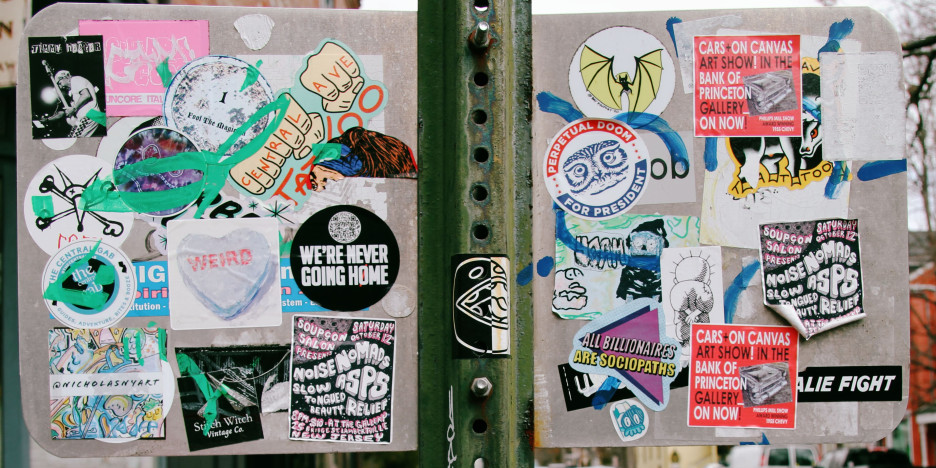 An array of stickers on the back of a street sign.