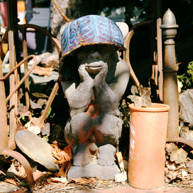 a monkey gargoyle statue wearing a bowl for a hat
