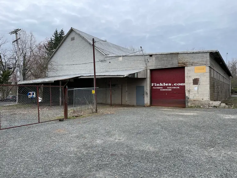 an old cinder block building with a large garage that has a sign painted on it that reads “Finkles, plumbing, electric, hardware”