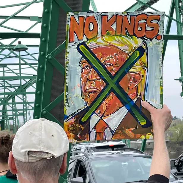 a protest sign with an X through an image of trump and the words read &lsquo;NO KINGS&rsquo;