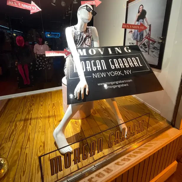 a mannequin in a window with signs pointing next door