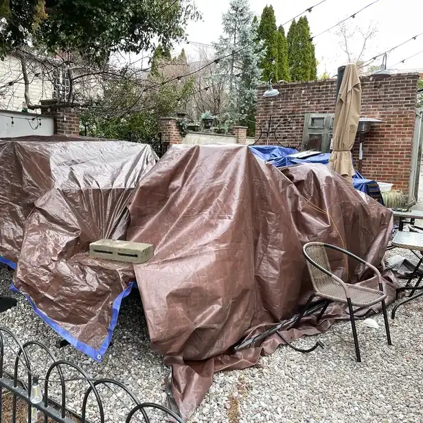 a brown tarp covers outdoor patio tables and chairs