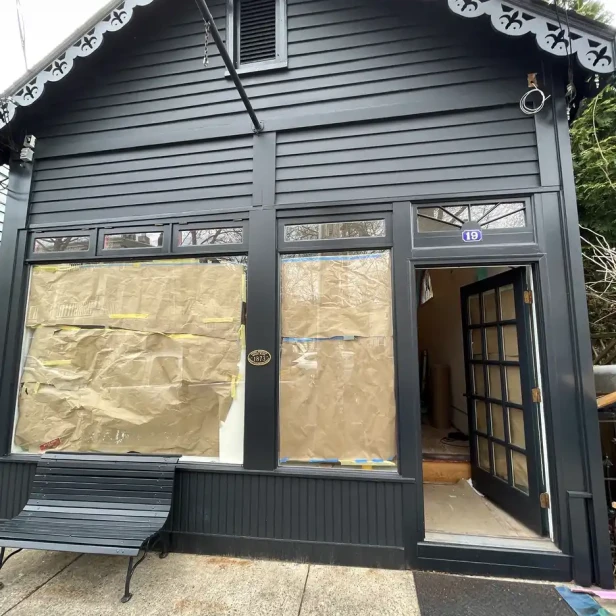 the black facade of a small shop with paper on the windows