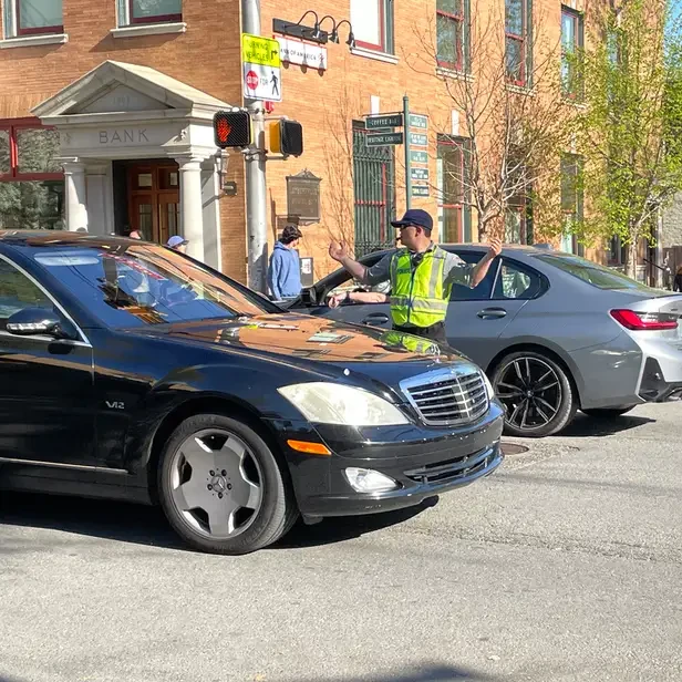 a man directing traffic as two cars pass him