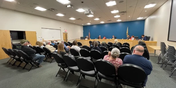 people sitting in chair listening to the city council speak at a council meeting