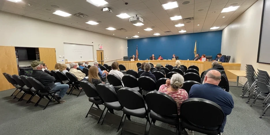 people sitting in chair listening to the city council speak at a council meeting