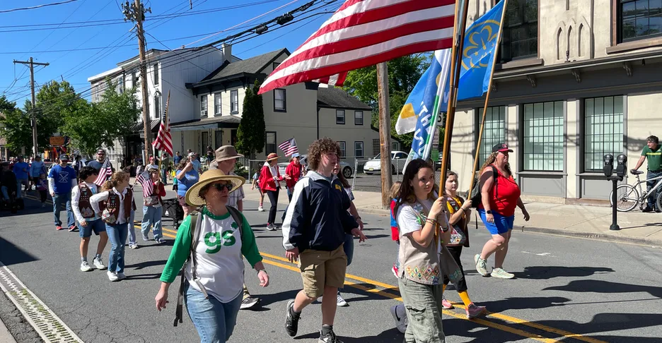 Girls Scouts march down Main Street led by several girls holding flags