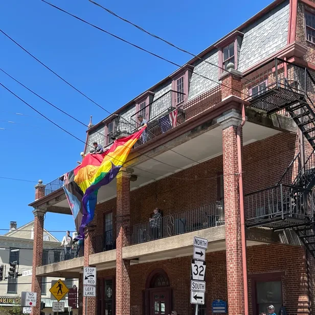 people on a third floor balcony releasing a flag over the edge