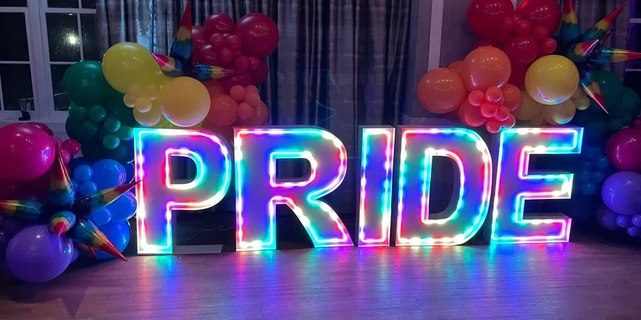 a glowing, colorful 3D sign that reads PRIDE