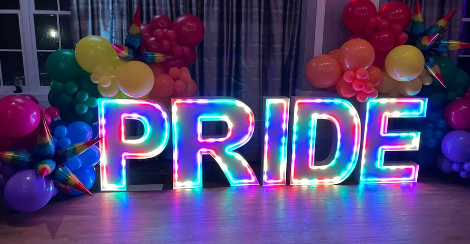 a glowing, colorful 3D sign that reads PRIDE