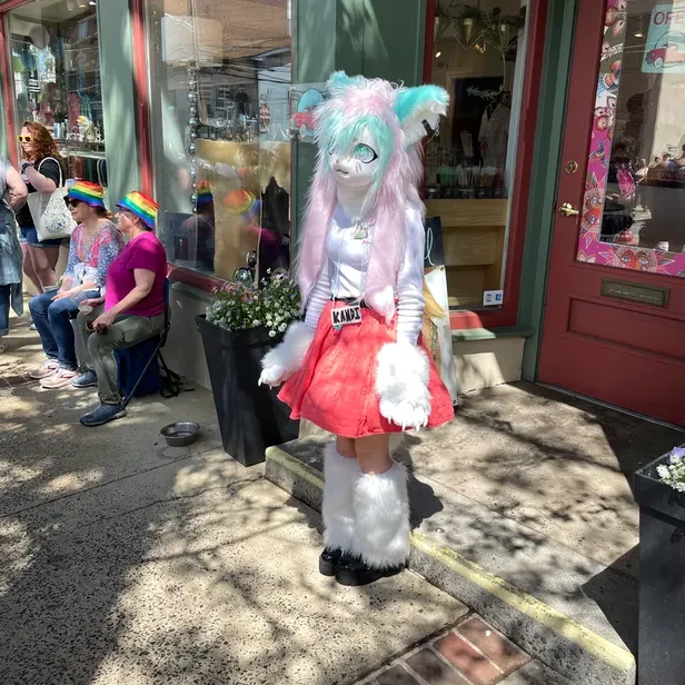 a candy-colored furry stands silent and alone at the parade
