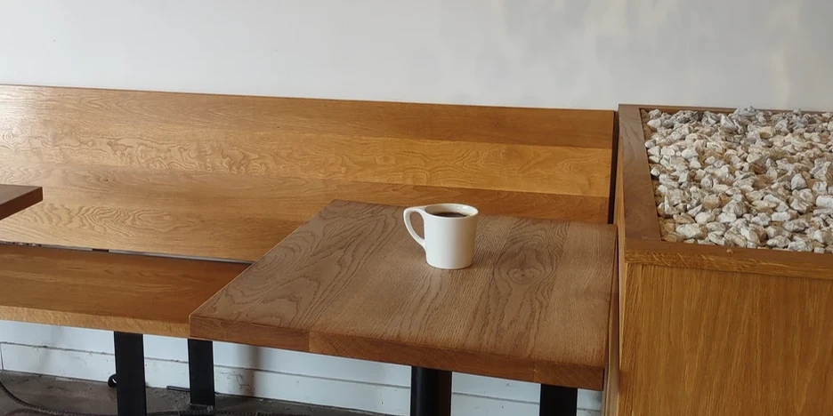 a lone coffee cup sitting on a wooden table in a coffehouse