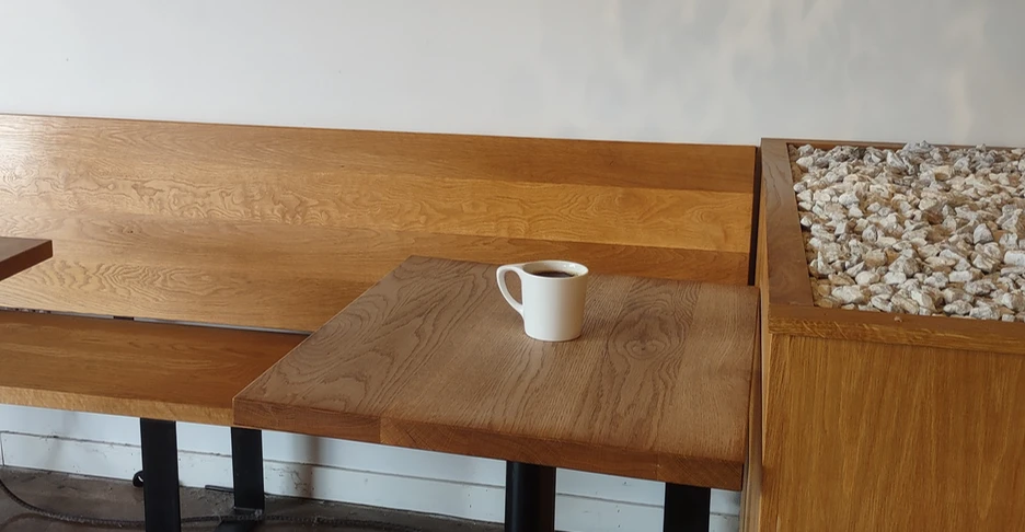 a lone coffee cup sitting on a wooden table in a coffehouse