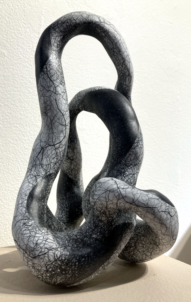 a sculpture of twisted black material with a light gray texture on the skin