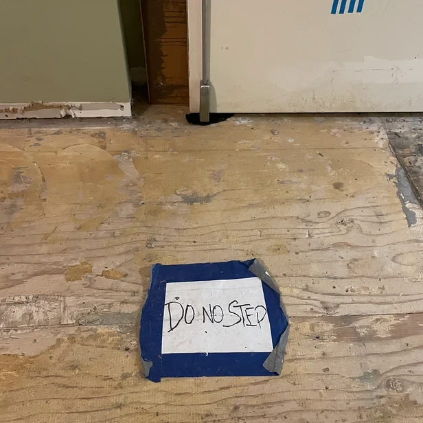 a sign that reads, &ldquo;DO NO STEP&rdquo; is duct taped to the floor