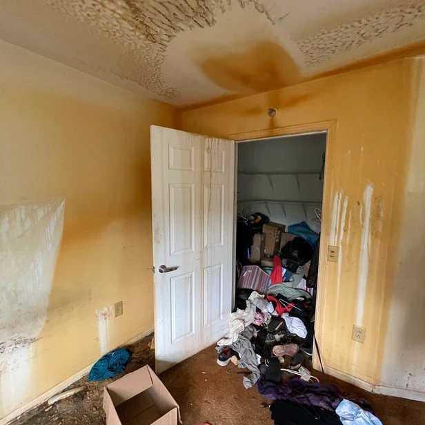 the bedrooom of Linda&rsquo;s old apartment covered in rust stains, the walk-in closet door is open and old clothes spill out