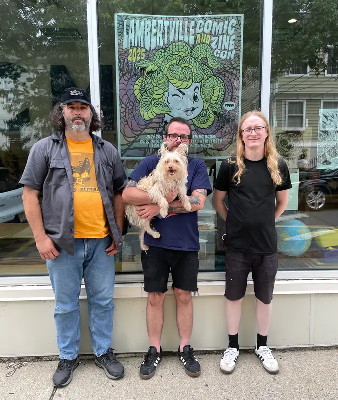 T, Henri, and Mike stand in front of the official 2025 Comic and Zine Conference poster