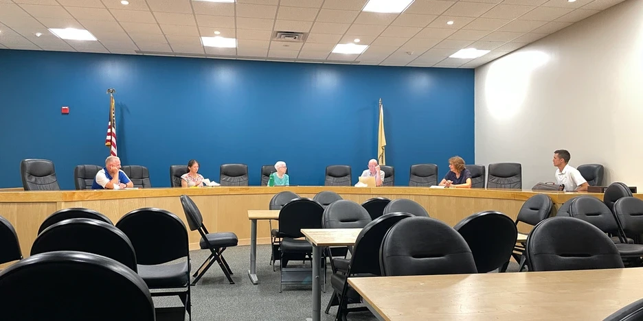 six committee board members sitting in chairs at the dais and talking