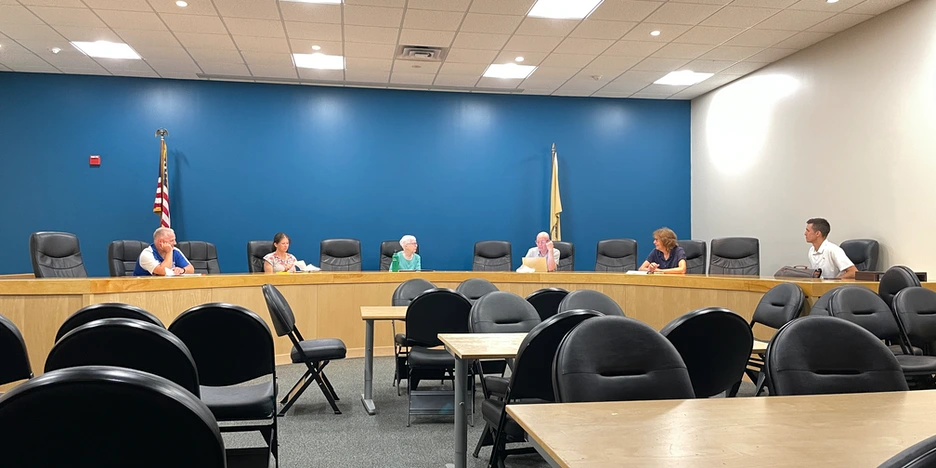 six committee board members sitting in chairs at the dais and talking