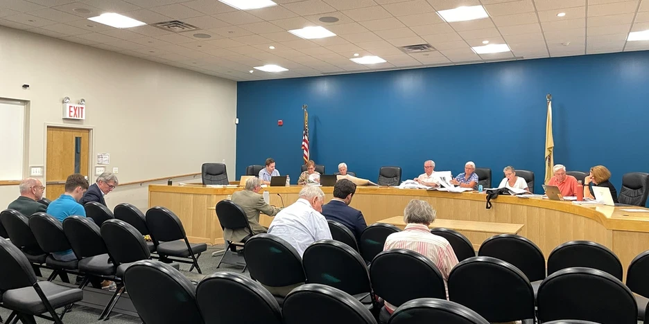 the planning board sitting at a dias, with other people sitting in chairs around the room