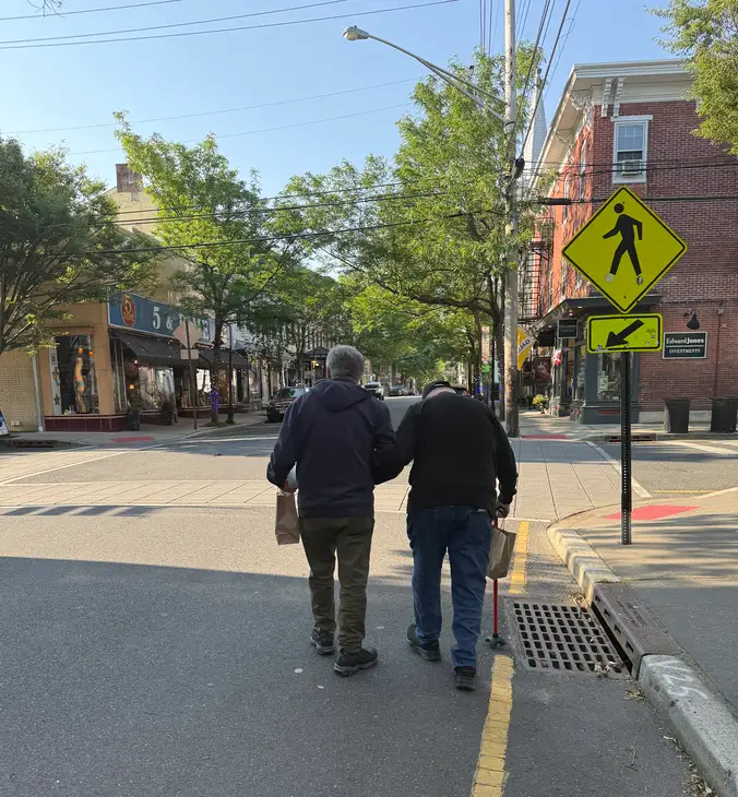 a man helping Sarge walk down the street
