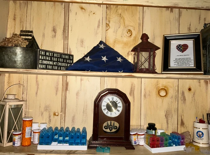 a tri-folded flag simply displayed on a shelf, below are pills and medicines