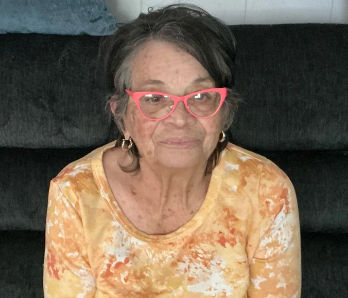 a woman wearing pink glasses, sitting on a couch