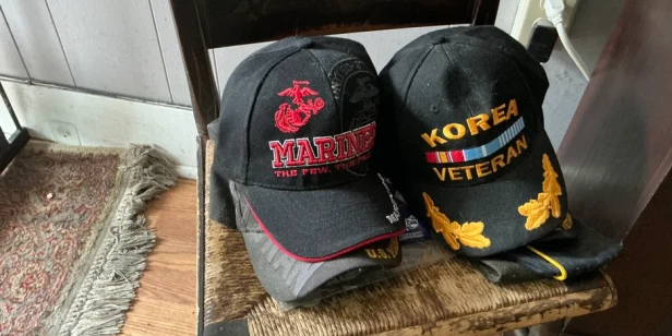 several military logo baseball caps sitting on a chair by the door