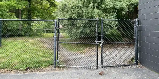 a closed fence gate with a chain and padlock holding it shut