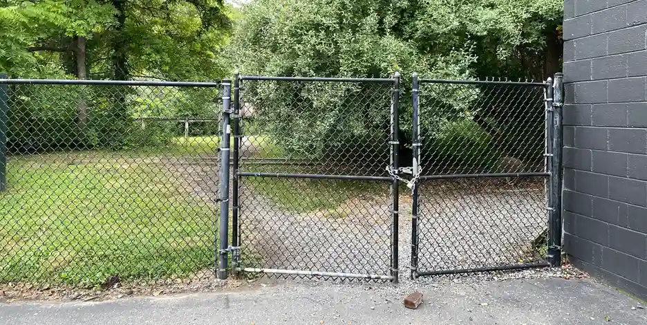 a closed fence gate with a chain and padlock holding it shut