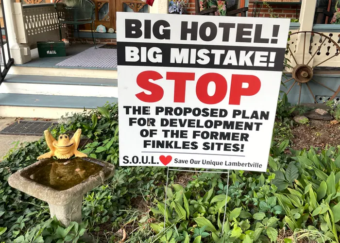 a sign in the front yard, next to a bird bath. it reads, “Big Hotel! Big Mistake!”