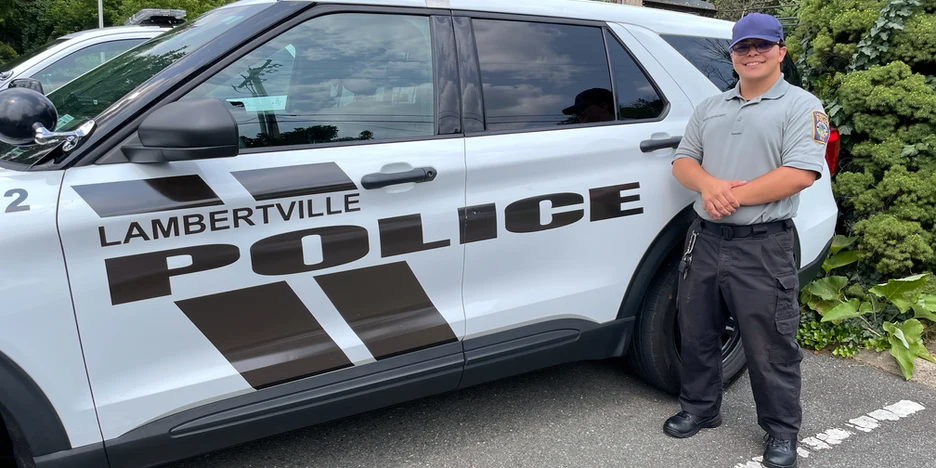 Jack smiling in his uniform while standing next to a police vehicle