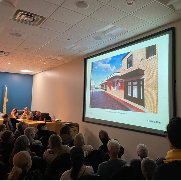 people looking up at a slide image of planned construction projected on the wall