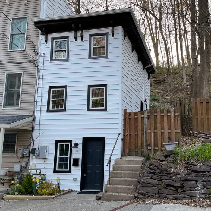 a small, three-story white house with black trim