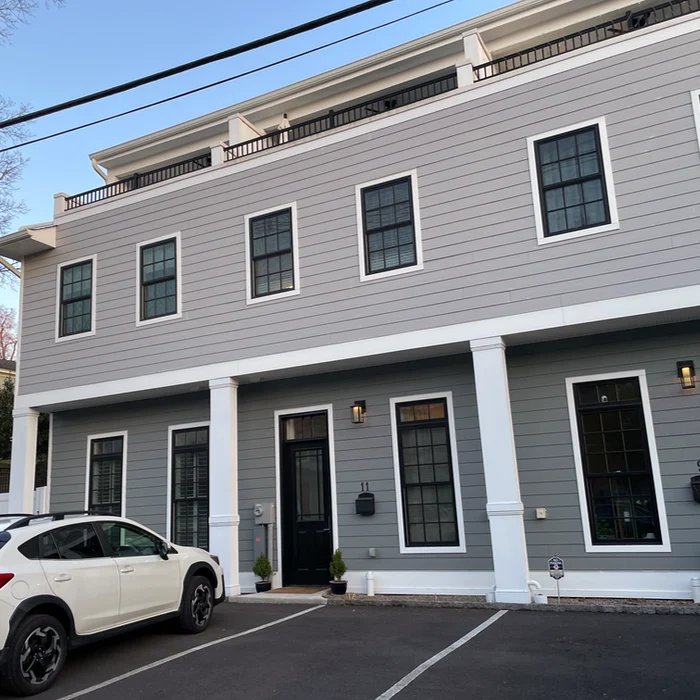 a gray townhouse with black windows and a balcony on the third floor